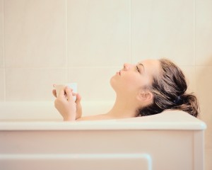 Woman Lying in a Bathtub Holding a Mug
